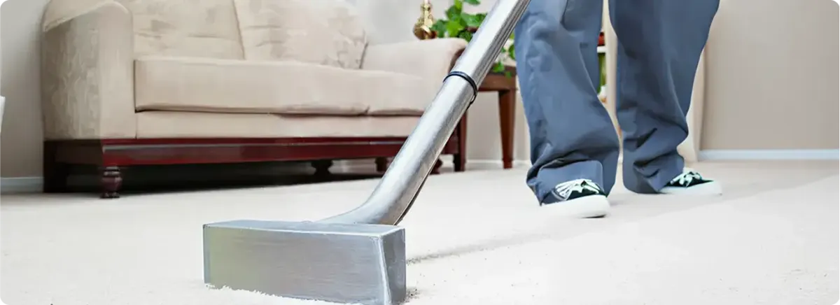 Carpet cleaning technician using a hot-water extraction wand on a light-colored carpet in a living room, Springfield, MO.