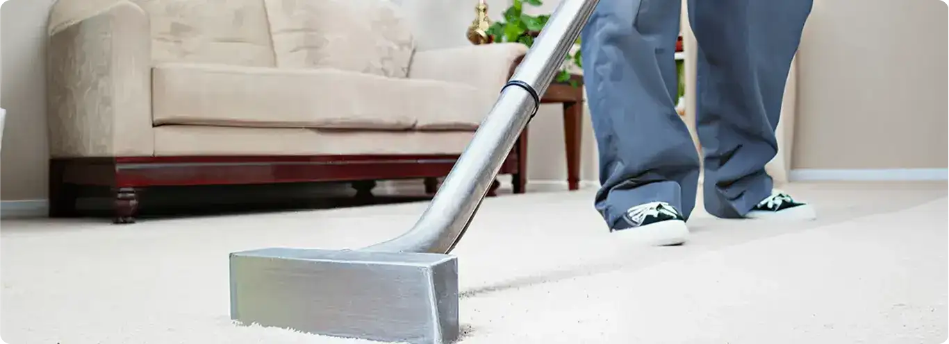 Carpet cleaning technician using a hot-water extraction wand on a light-colored carpet in a living room, Springfield, MO.